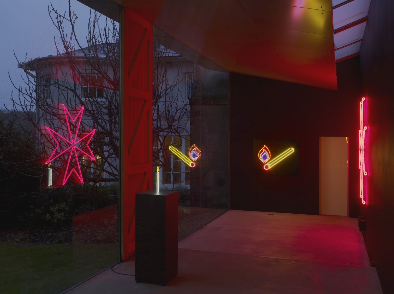 A yellow and red matchtstick with flame and a red neon maltese cross against black backdrops reflected a glass window