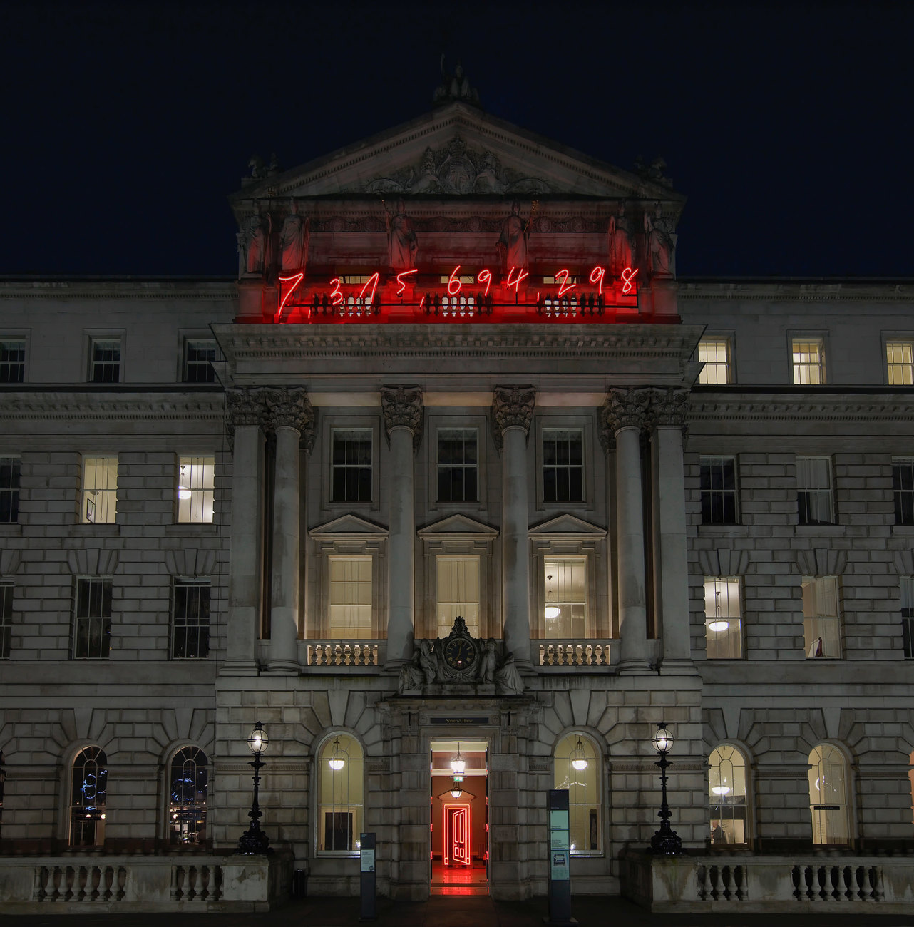 The facade of Somerset House with a large red neon sign displaying the number 7,315,694,298 - the estimated population of the world at 6pm of Tuesday 17 March 2015