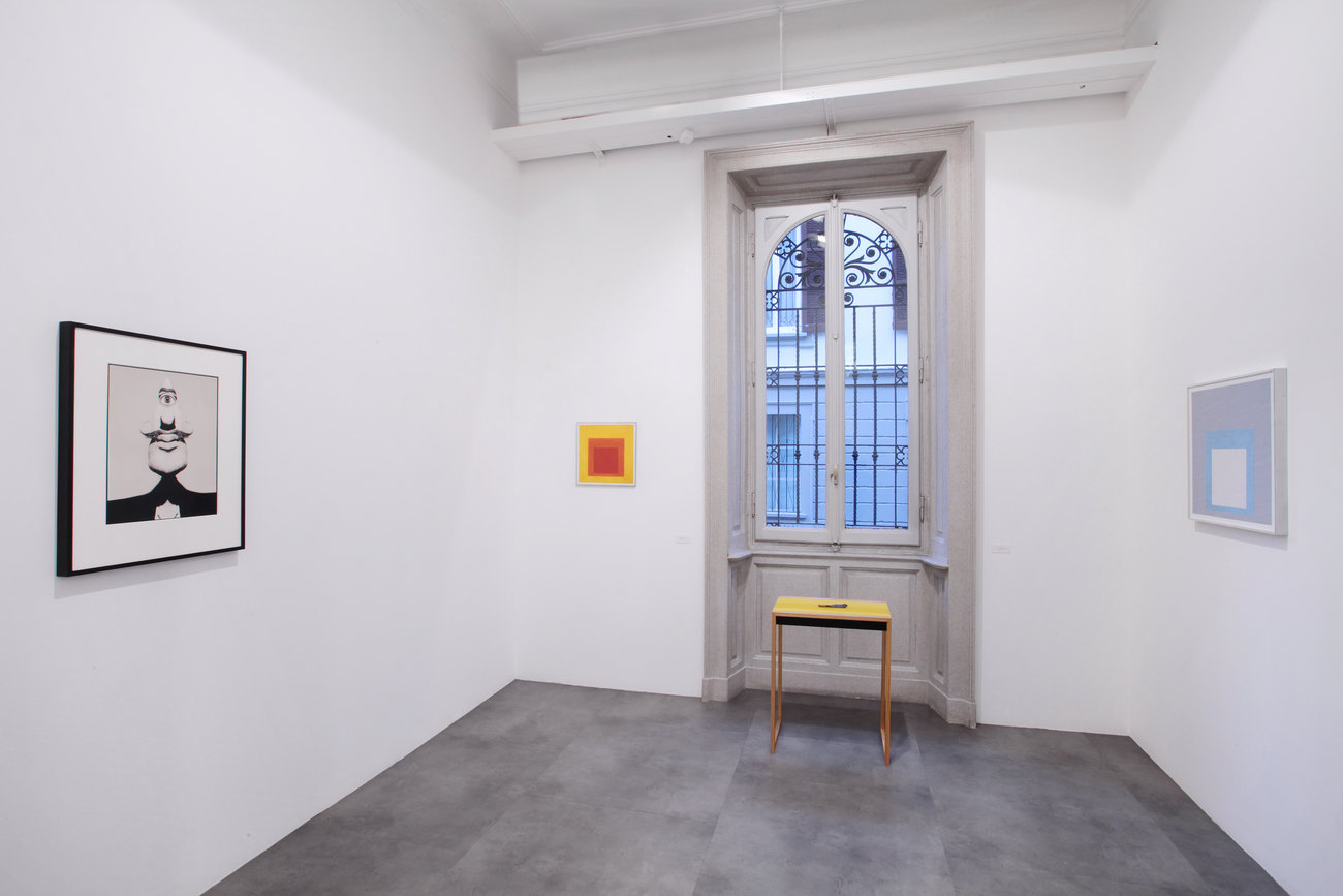 A series of artworks in a small room in a gallery with black floors and white walls