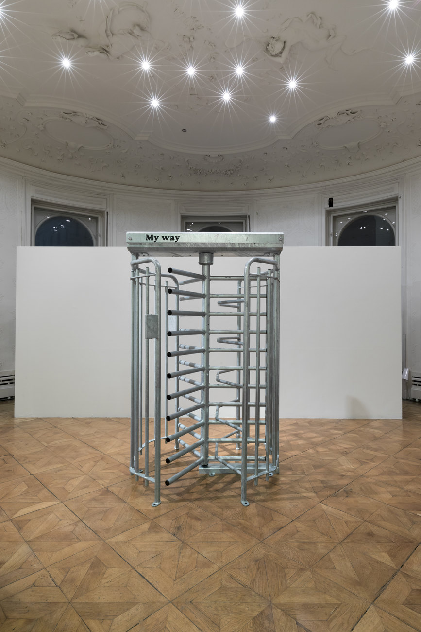 A freestanding grey metal turnstile with the words, "MY WAY" printed above