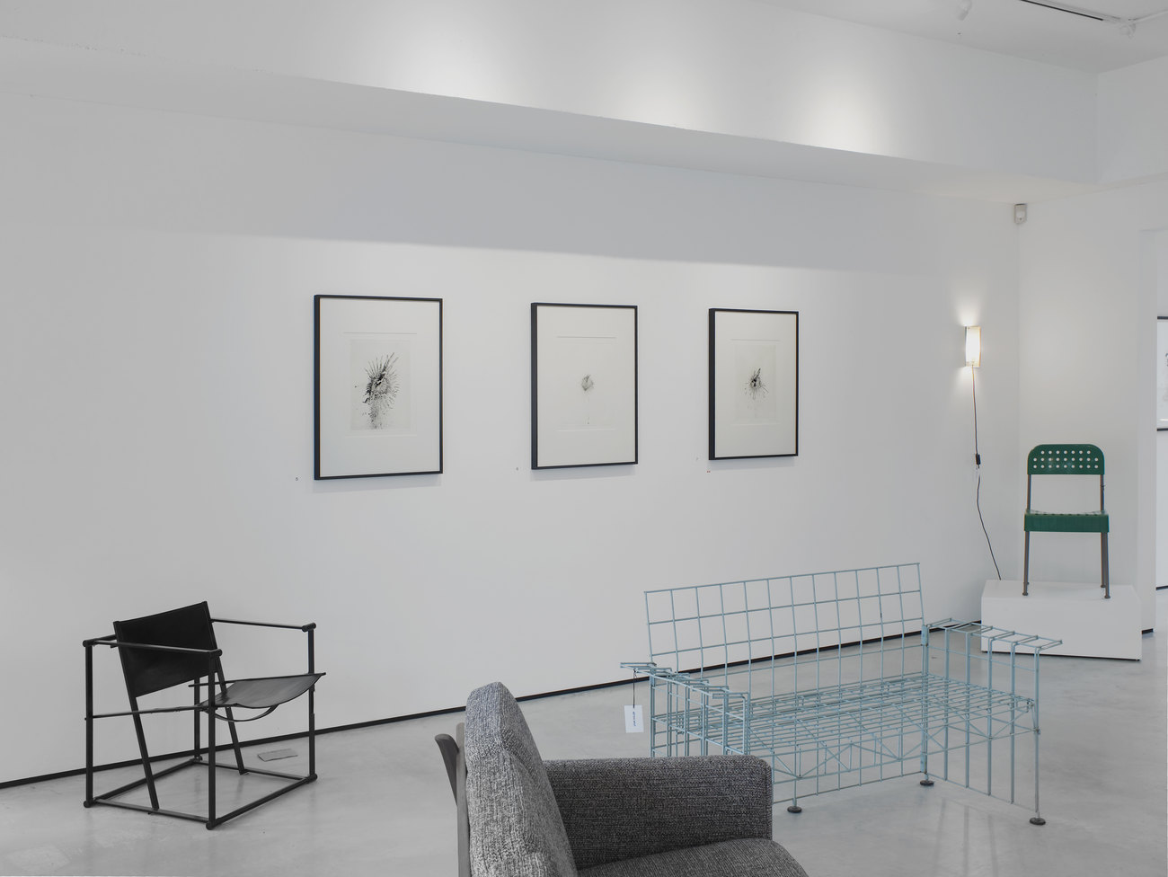 4 chairs in a room, there are three framed images on a white wall behind