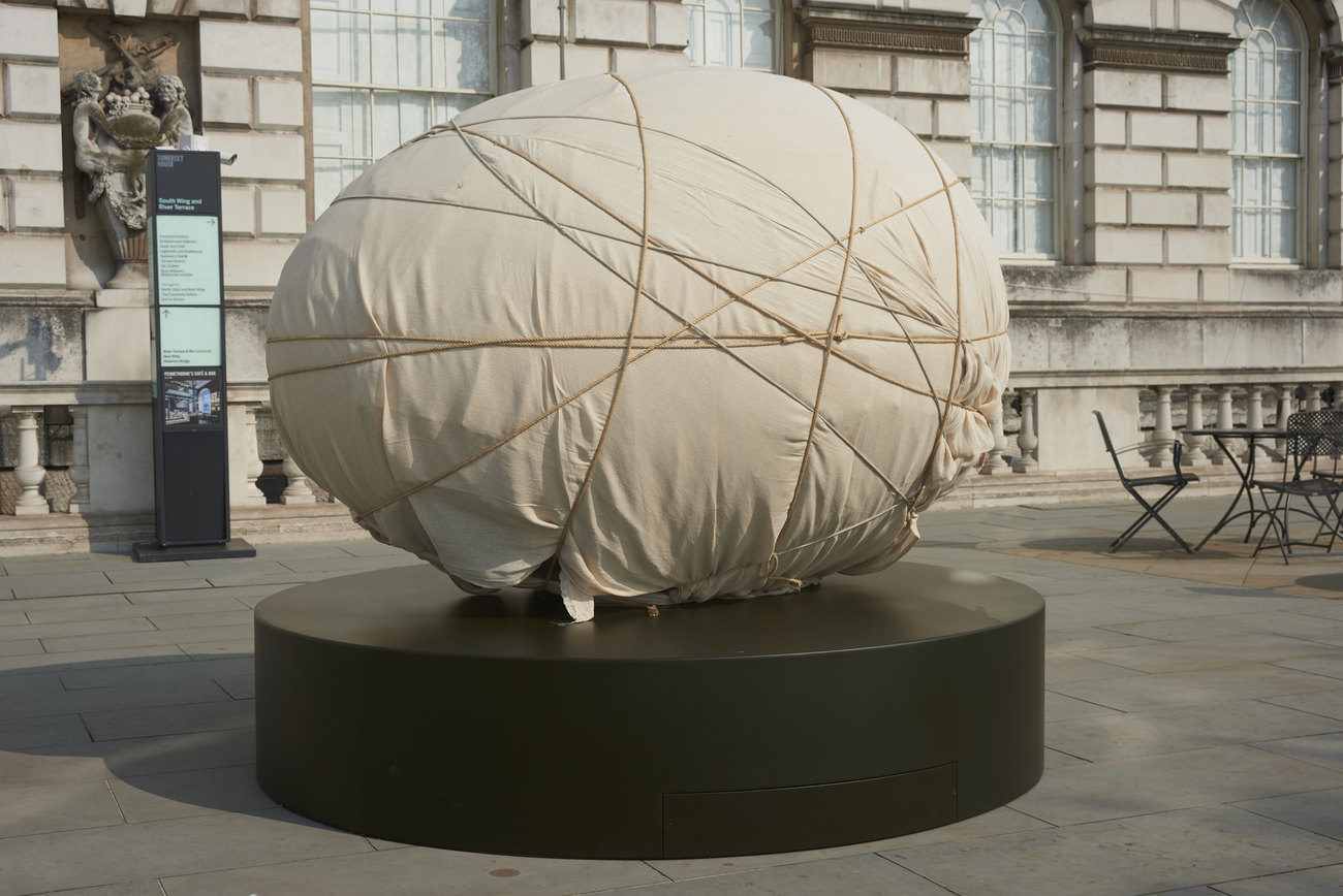 A giant egg wrapped in a dust sheet with string