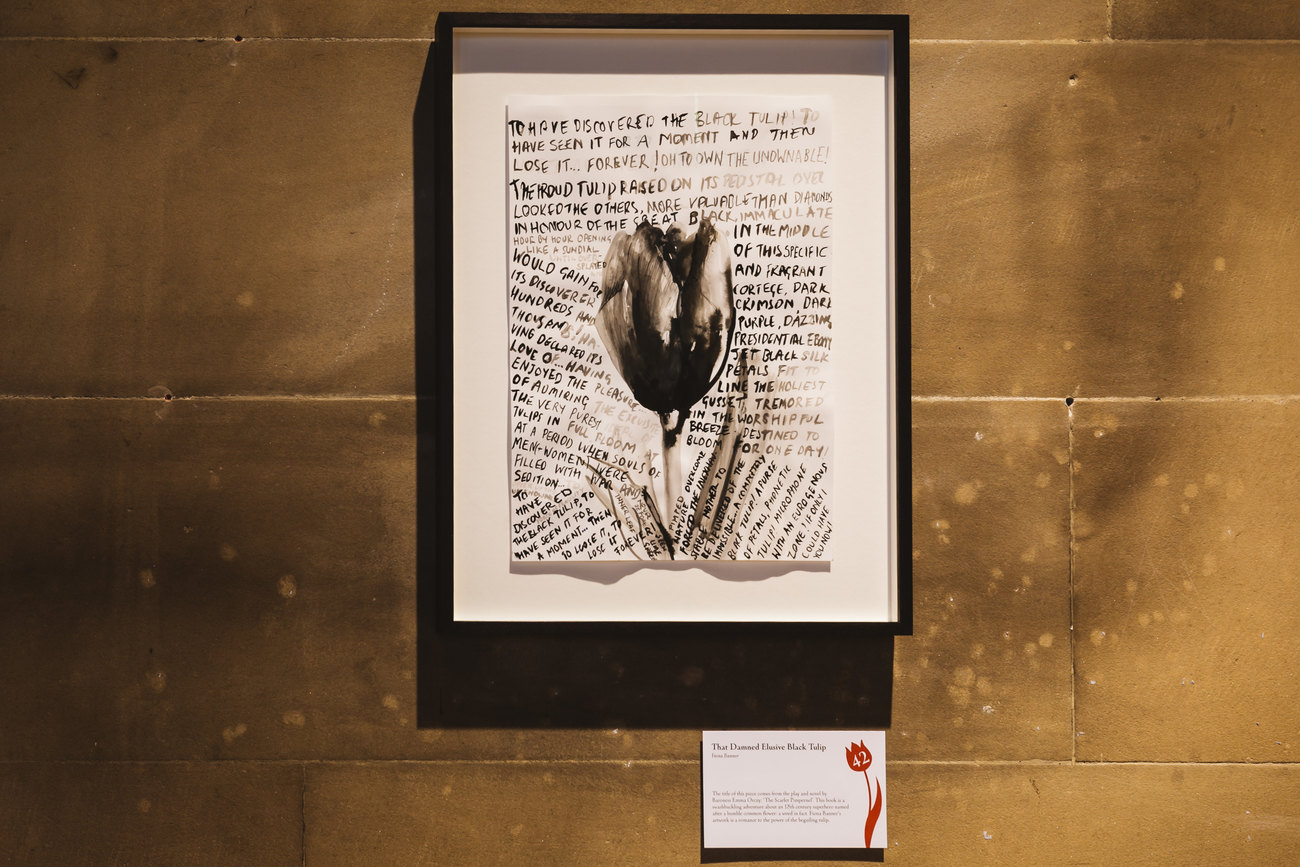 An image shows a black tulip painted with text, the artwork is by Fiona Banner 
