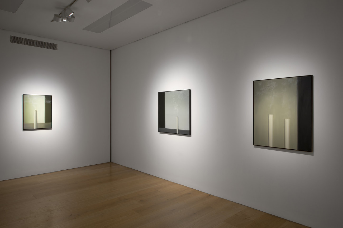 Installation photo of paintings with just extinguished candles