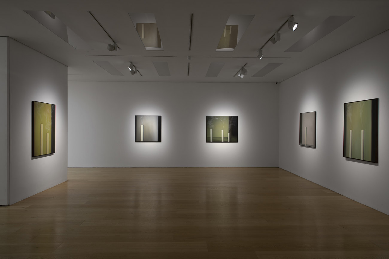 Installation photo of paintings with just extinguished candles 