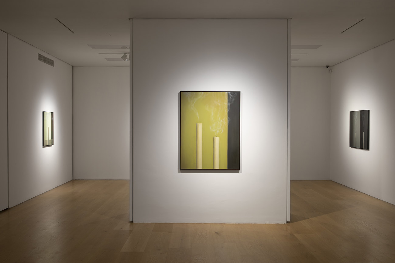 Installation photo of paintings with just extinguished candles