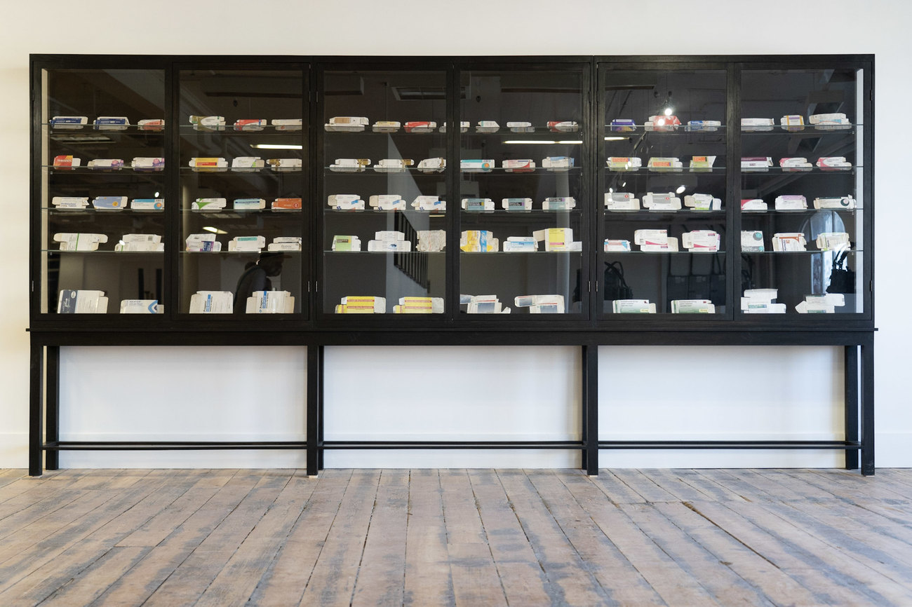 Picture is a black cabinet filled with used and discarded medicine boxes