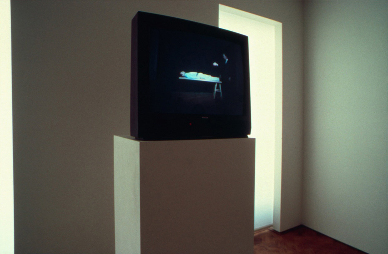 A television shows the artist enacting a magic trick