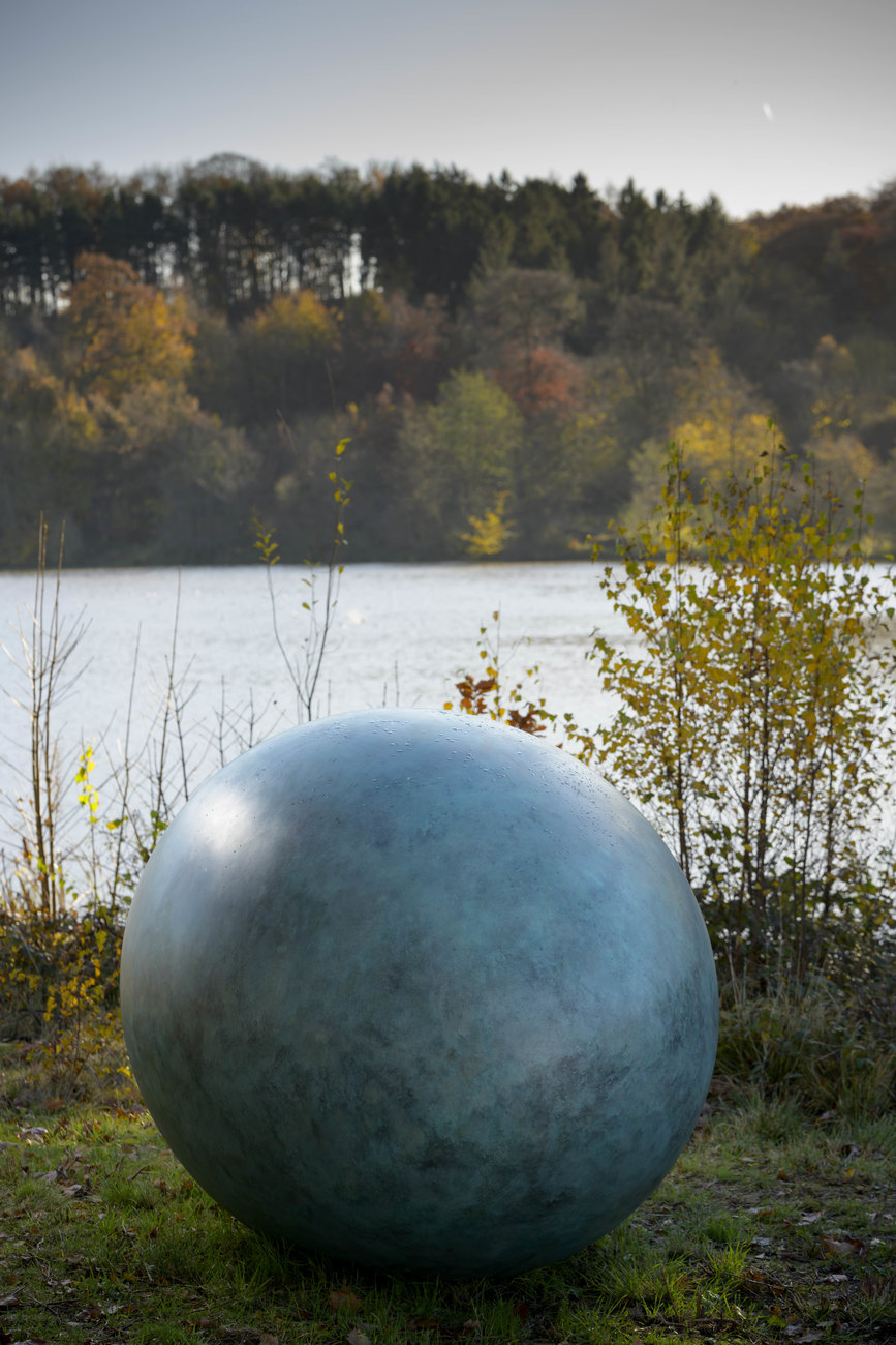Sculpture of a Bronze Duck Egg in front of a pond